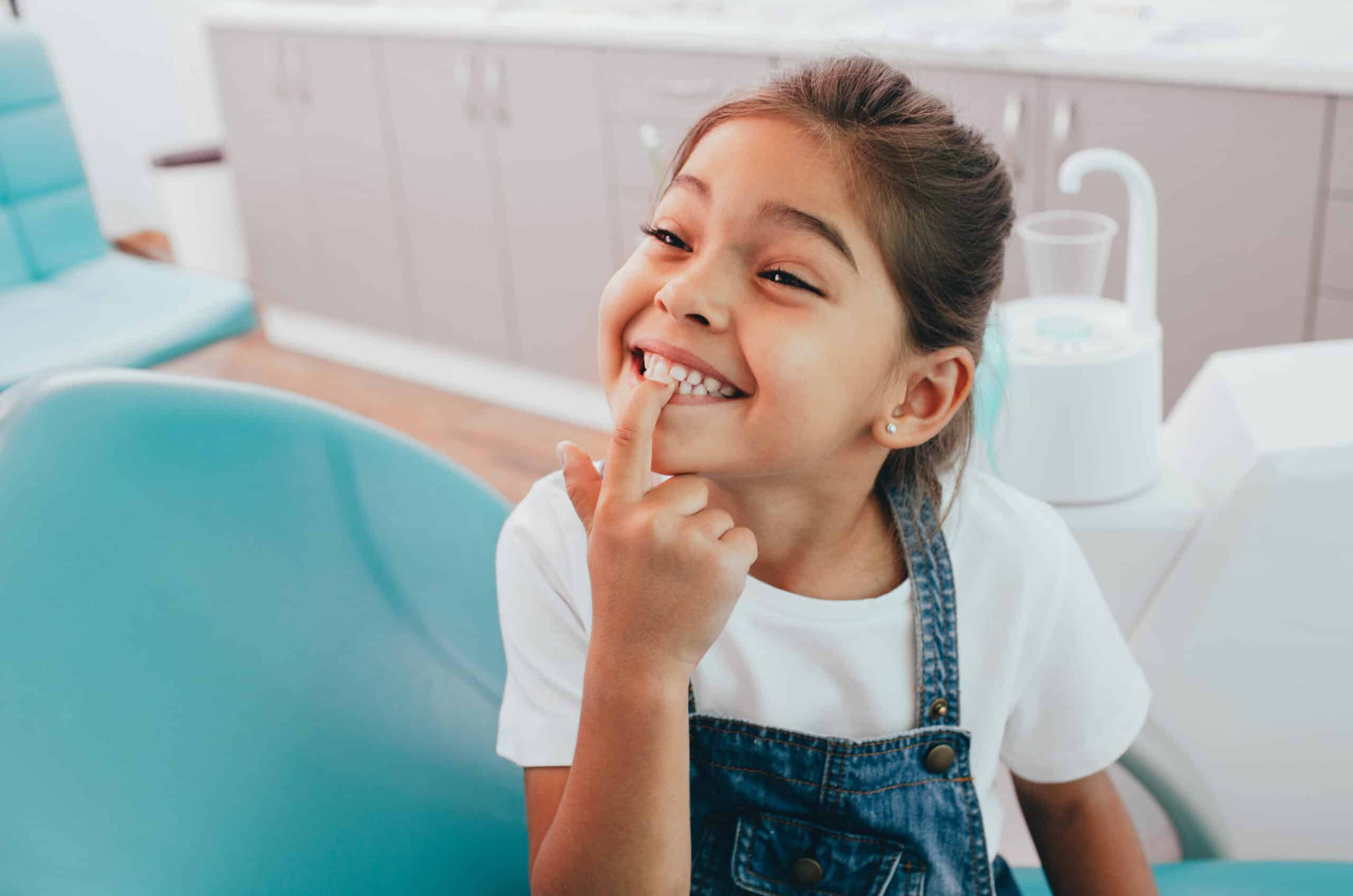 little patient showing her perfect toothy smile while sitting dentists chair